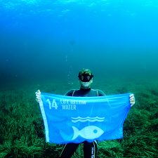 Tidligere verdensmester i fridykning Umberto Pelizzari hejser et flag i Middelhavet med mål 14: Livet i Havet. Foto: Enric Sala